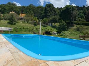 a blue swimming pool with a view of a garden at Chalé Jambeiro - Refúgio da Mata in Paty do Alferes