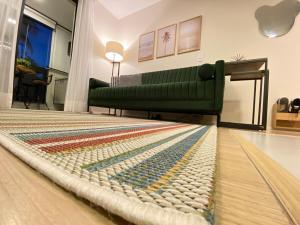a living room with a green couch and a rug at Loft Sou Mais Icaraí in Niterói