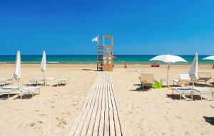 ein Sandstrand mit Stühlen und einem Rettungsschwimmerturm in der Unterkunft 1 Bedroom Cozy Home In Marina Di Modica in Marina di Modica