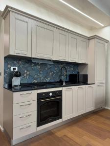 una cocina con armarios blancos y horno negro en APARTAMENT - Torino Home Living, en Turín