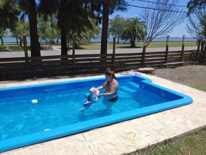 a woman playing with a baby in a swimming pool at El Viejo Roble in Chascomús