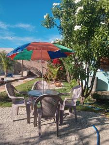 a table and chairs with a colorful umbrella at Chales Da Mata in Fortim