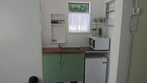 a small kitchen with a sink and a microwave at Cozy Haven - Waihi in Waihi