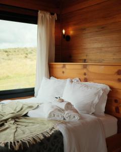 a bedroom with a bed with white sheets and a window at É diferente, descubra por quê in Urubici