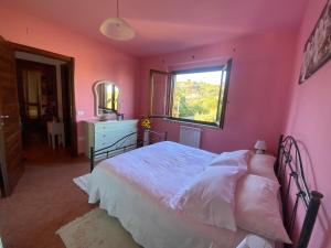 a pink bedroom with a bed and a window at Charming apartment with dreamy terrace in Arzachena