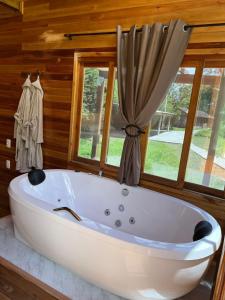 a white bath tub in a room with windows at Pousada e fazenda mato verde in São Bonifácio