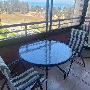 a glass table and two chairs in front of a window at Jardín del Mar in Viña del Mar
