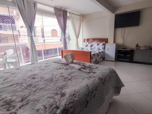 a bedroom with a bed and a large window at Suítes Bisi in Cabo Frio