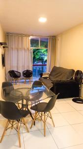 a living room with a glass table and chairs at Apartamento pé na areia em Praia de Rio das Ostras in Rio das Ostras