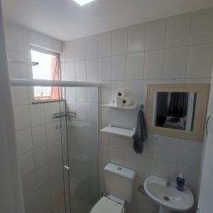 a white bathroom with a toilet and a sink at Apartamento pé na areia em Praia de Rio das Ostras in Rio das Ostras