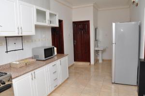 cocina con armarios blancos y nevera blanca en Muyenga Luxury Vacation Home, en Kampala