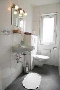 a white bathroom with a sink and a toilet at Hirschen B&B in Maienfeld