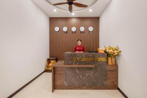 Eine Frau, die hinter einem Podium in einem Raum steht. in der Unterkunft Kly Luxury Hotel in Hue