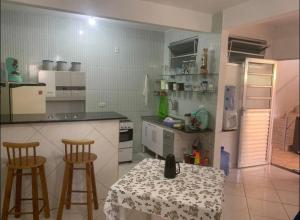 una cucina con tavolo, due sgabelli, tavolo e bancone di Casa Para Veraneio em Ilhéus - Zona Sul a Ilhéus Altre 25 foto