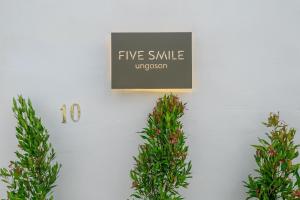 a sign on a wall with two plants at Villa Five Smile Ungasan in Badung +8 photos