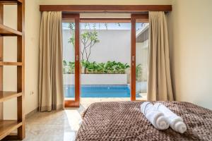 a bedroom with a bed and a view of a pool at Villa Five Smile Ungasan in Badung
