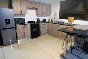 ハボローネにあるCandlewood Apartment 8のキッチン(冷蔵庫、テーブル付)
