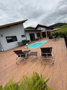a patio with chairs and a pool in front of a house at Refúgio nascer das águas in Gravatal