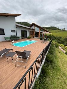 a wooden deck with chairs and a swimming pool at Refúgio nascer das águas in Gravatal