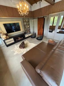 a living room with a brown leather couch and a fireplace at Refúgio nascer das águas in Gravatal