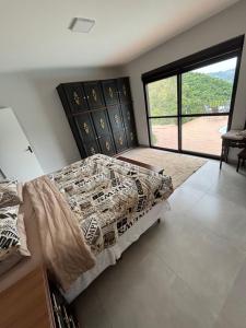 a bedroom with a bed and a large window at Refúgio nascer das águas in Gravatal