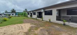 a house with a grass yard next to a building at Prasad Apartments in Labasa