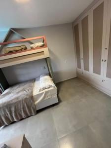 a bedroom with a bed and a bunk room with cabinets at Refúgio nascer das águas in Gravatal