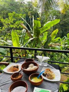a table with plates of food on a balcony at Rainforest Mask villa in Deniyaya +23 photos