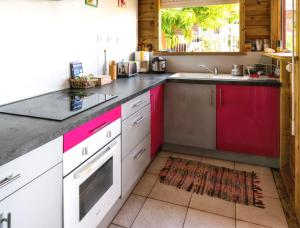 a kitchen with red and white cabinets and a sink at Bungalow charmant proche de Bouillante avec climatisation. in Bouillante +14 photos