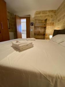 a large white bed with two towels on it at L'Alba dei Sogni in Marina Serra