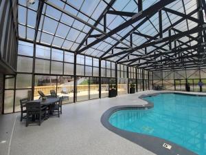 une grande piscine intérieure avec un plafond en verre, une table et des chaises dans l'établissement Beautiful Bear Haven, à Sevierville