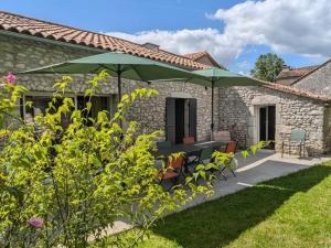 eine Terrasse mit einem Tisch und einem grünen Sonnenschirm in der Unterkunft Maison rénovée avec jardin et espace détente proche Bergerac - FR-1-616-425 in Razac-de-Saussignac