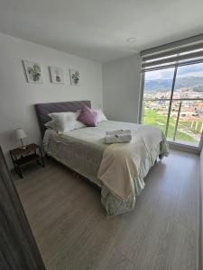 a bedroom with a large bed and a large window at Increíble apartamento con vista panorámica al lago Sochagota in Paipa