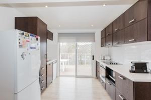 a kitchen with a white refrigerator and wooden cabinets at 46 Banjo Patterson Crescent in Jindabyne