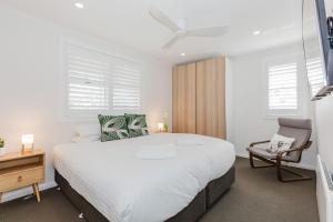a white bedroom with a large bed and a chair at 46 Banjo Patterson Crescent in Jindabyne