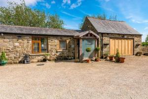 ein Steinhaus mit Garage und Topfpflanzen in der Unterkunft Meagill Cottage Sleeps 4 with Hot Tub & Parking in Otley