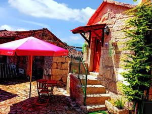 einen roten Regenschirm neben einem Haus mit Treppe in der Unterkunft Comfortable house in Lindoso, stunning mountain view in Pedras de Moledo