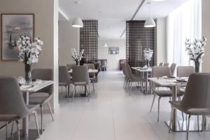 a dining room with tables and chairs and flowers at Jarzez Hotel Apartments Al Hail in Seeb