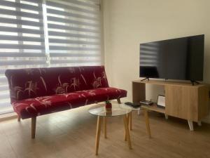 a living room with a red couch and a flat screen tv at Asturias La Serena in La Serena
