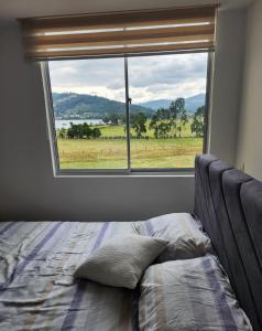 a bedroom with a bed and a large window at Apartamento de lujo frente al Lago Sochagota in Paipa