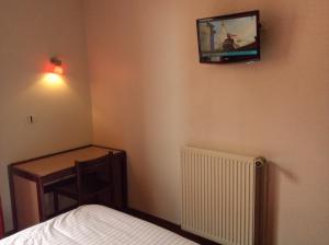 a bedroom with a bed and a tv on the wall at Hotel De La Place in Malakoff