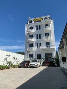 a white building with two cars parked in front of it at khách Sạn Hoạt Thúy in Teurnoum