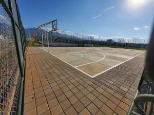 un campo da tennis con rete e canestro da basket di Santa Ana Maquilishuat a Santa Ana
