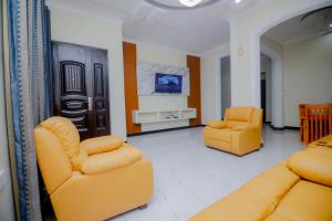 Una sala de estar con dos sillas amarillas y un televisor. en Zanzibar home Residence, en Zanzíbar