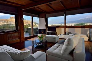 una sala de estar con muebles blancos y ventanas grandes. en KARYATIS LUXURY MAISONETTE by K&K en Atenas