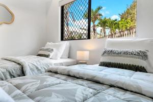 三一海滩Trinity Hideaway - Trinity Beach的一间带窗户的白色房间里有两张床