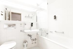 a white bathroom with a sink and a toilet at Hotel am Tiergarten in Karlsruhe
