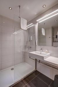 a white bathroom with a sink and a shower at Mezzo Hotel & Business in Beringen