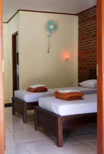 two twin beds in a room with a fan at Penginapan Homestay Mudiyono Syari'ah in Borobudur