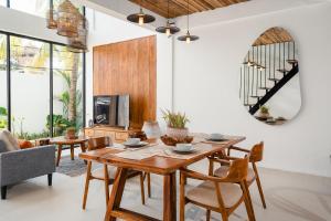 a dining room with a wooden table and chairs at Villa Casa Goya - Lofty Pool Villa Near The Beach in Vibrant Legian in Legian